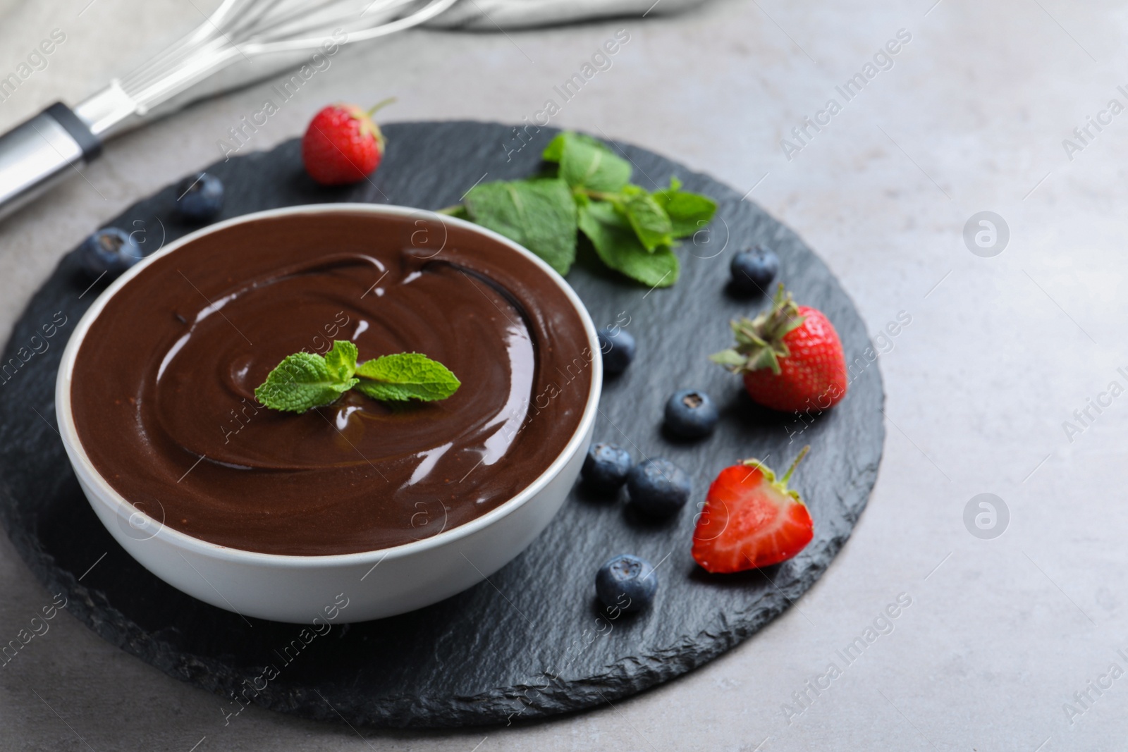 Photo of Delicious chocolate cream with berries and mint on grey table, space for text