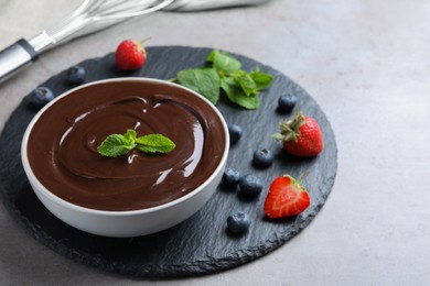 Photo of Delicious chocolate cream with berries and mint on grey table, space for text