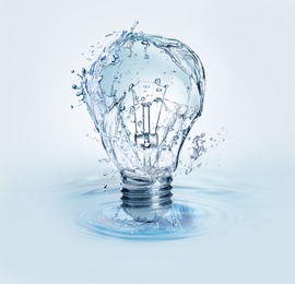 Light bulb with water splashes on light background. Alternative energy source