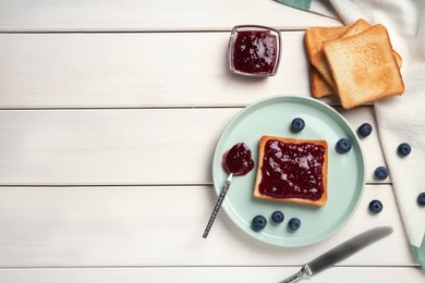 Photo of Toasts and blueberry jam served on white wooden table, flat lay. Space for text