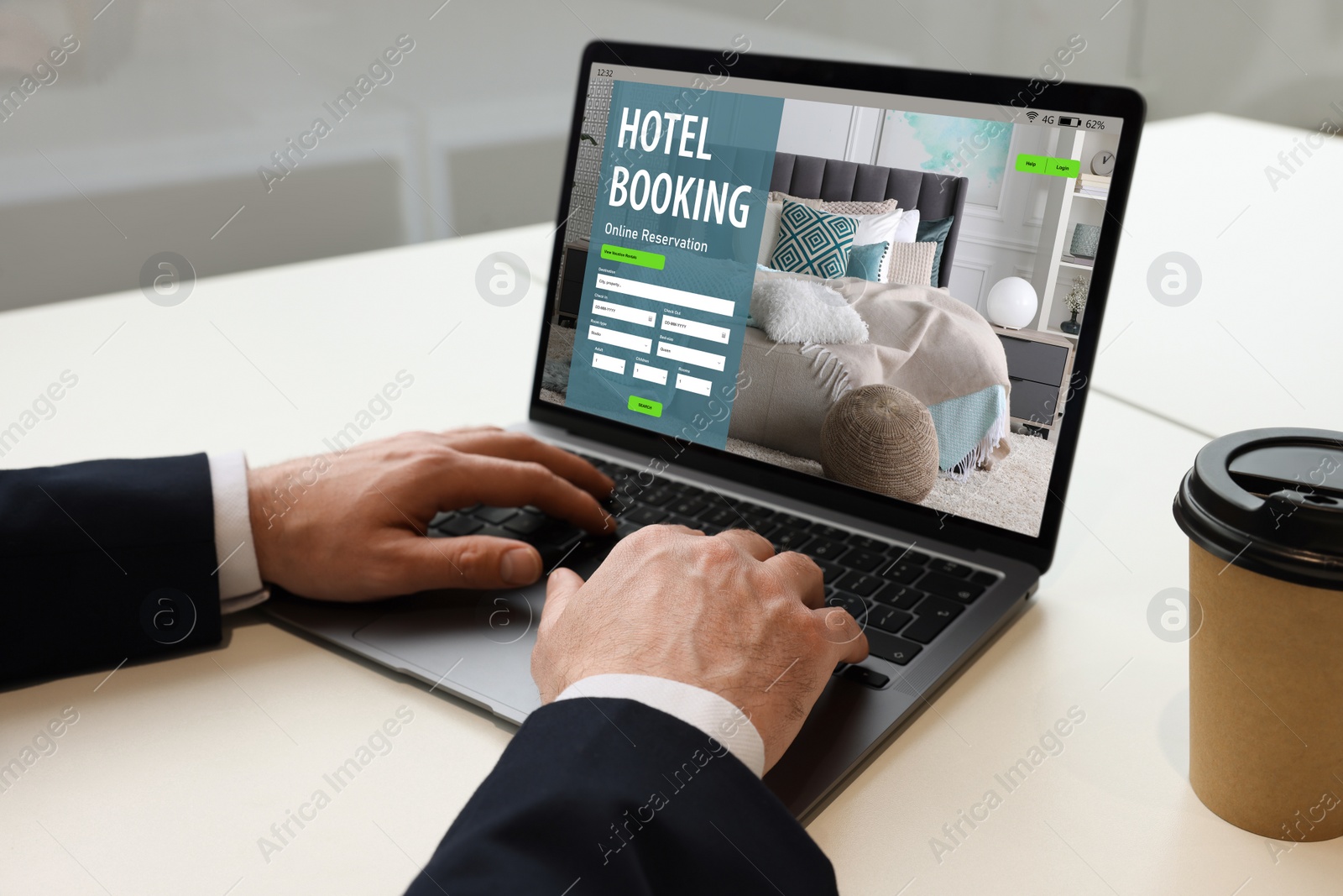 Image of Man using laptop to book hotel at white table, closeup