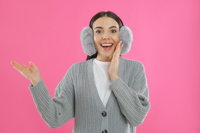 Photo of Beautiful young woman wearing earmuffs on pink background