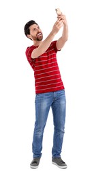 Smiling man taking selfie with smartphone on white background