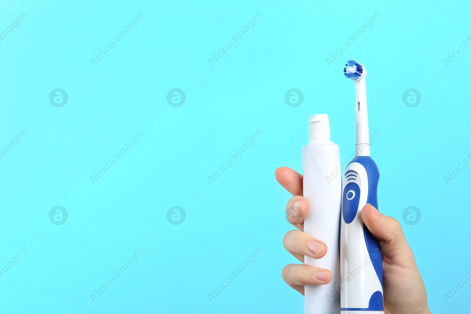 Photo of Woman holding electric toothbrush and paste on color background, space for text