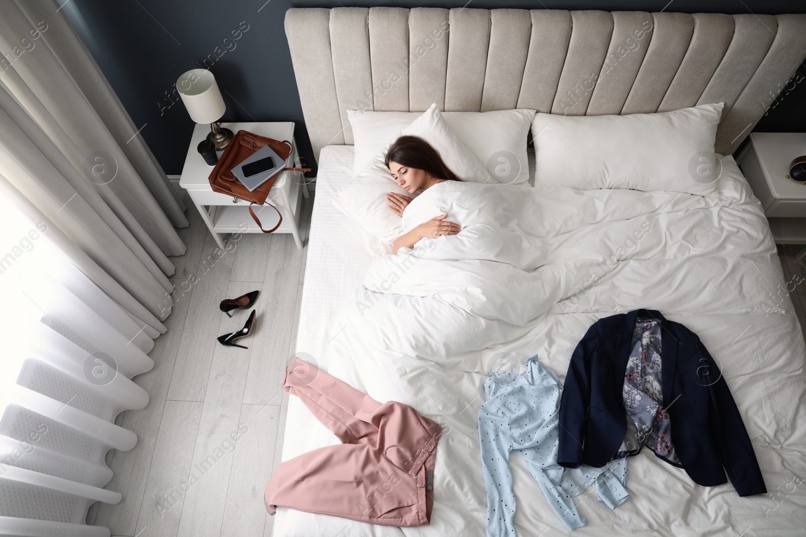 Photo of Tired woman sleeping in bed at home after work, above view