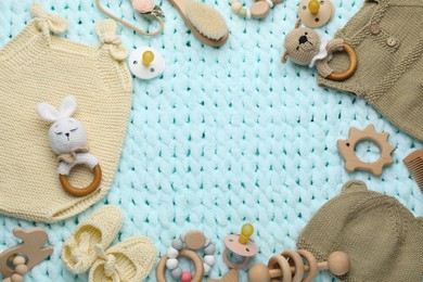 Frame of different baby stuff on light blue knitted fabric, flat lay. Space for text