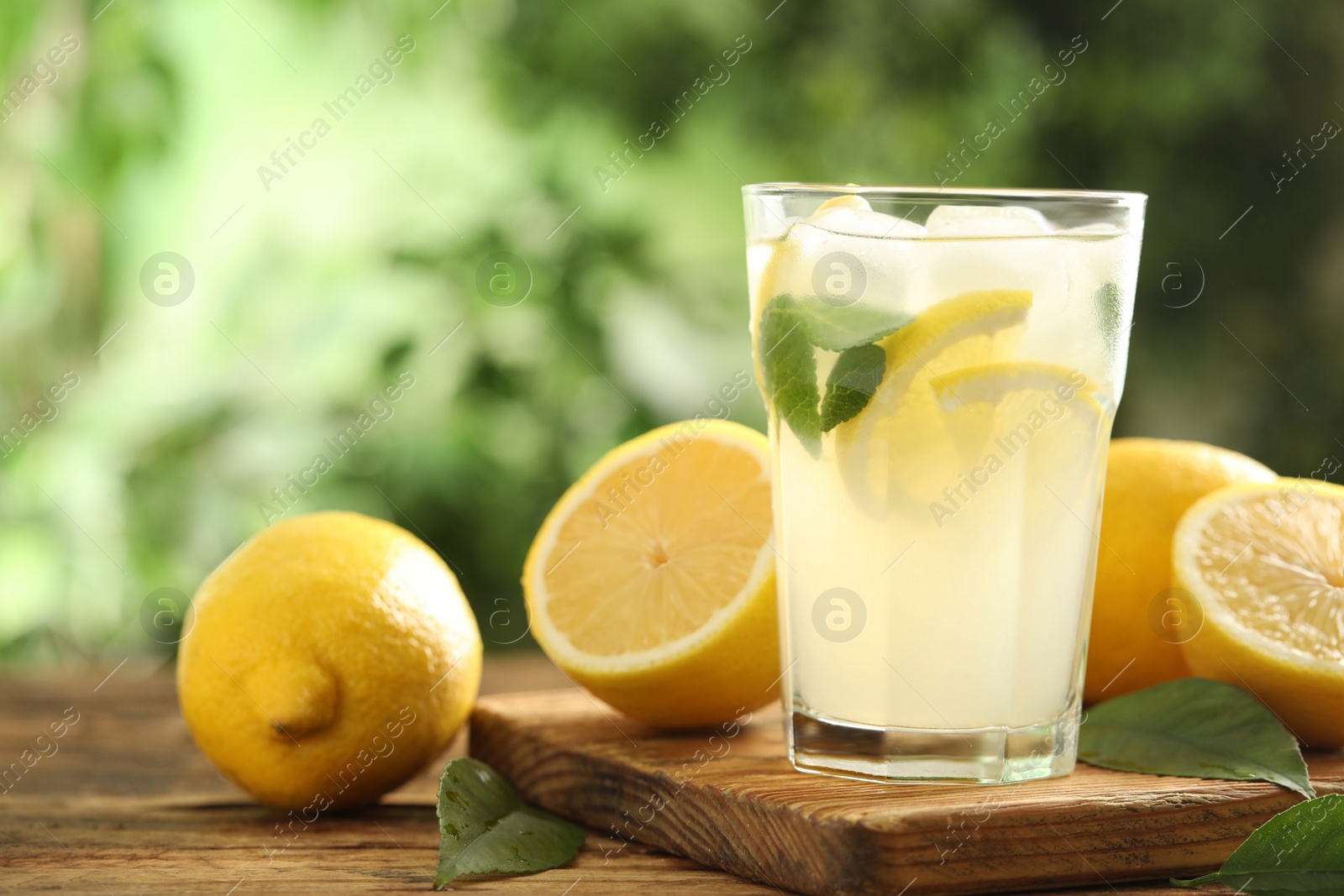 Photo of Cool freshly made lemonade and fruits on wooden table. Space for text