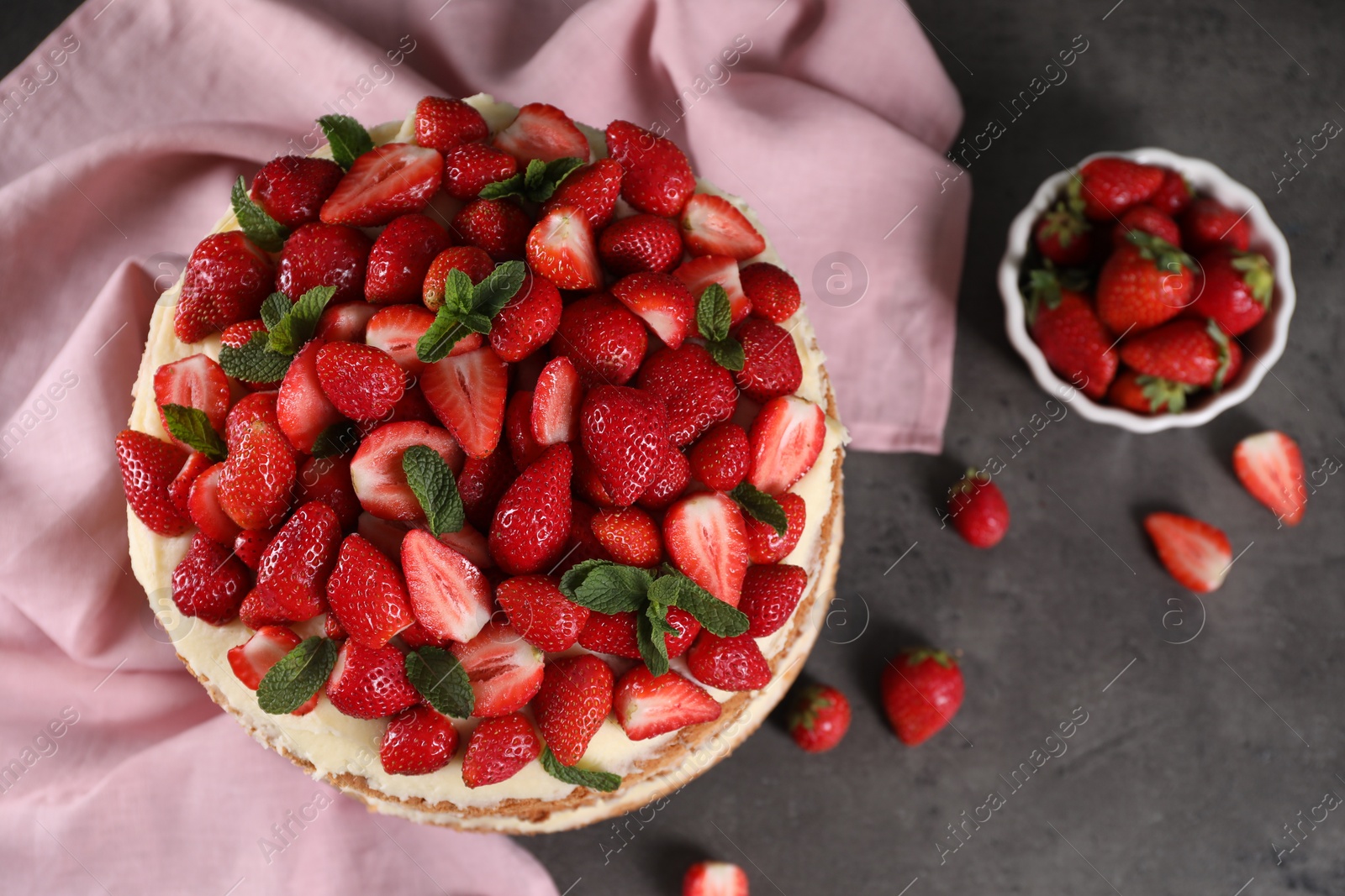 Photo of Tasty cake with fresh strawberries and mint on gray table, flat lay