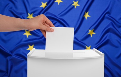 Image of Woman putting her vote into ballot box against flag of Europe, closeup