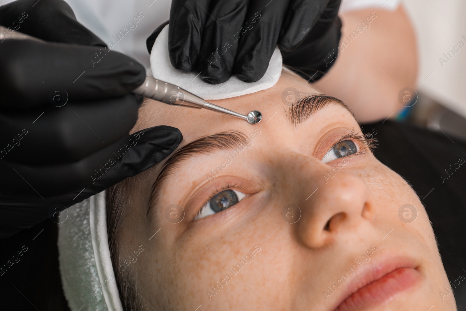 Photo of Cosmetologist using scrubber, closeup. Client having cleansing procedure