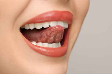 Woman showing her tongue on light background, closeup. Space for text
