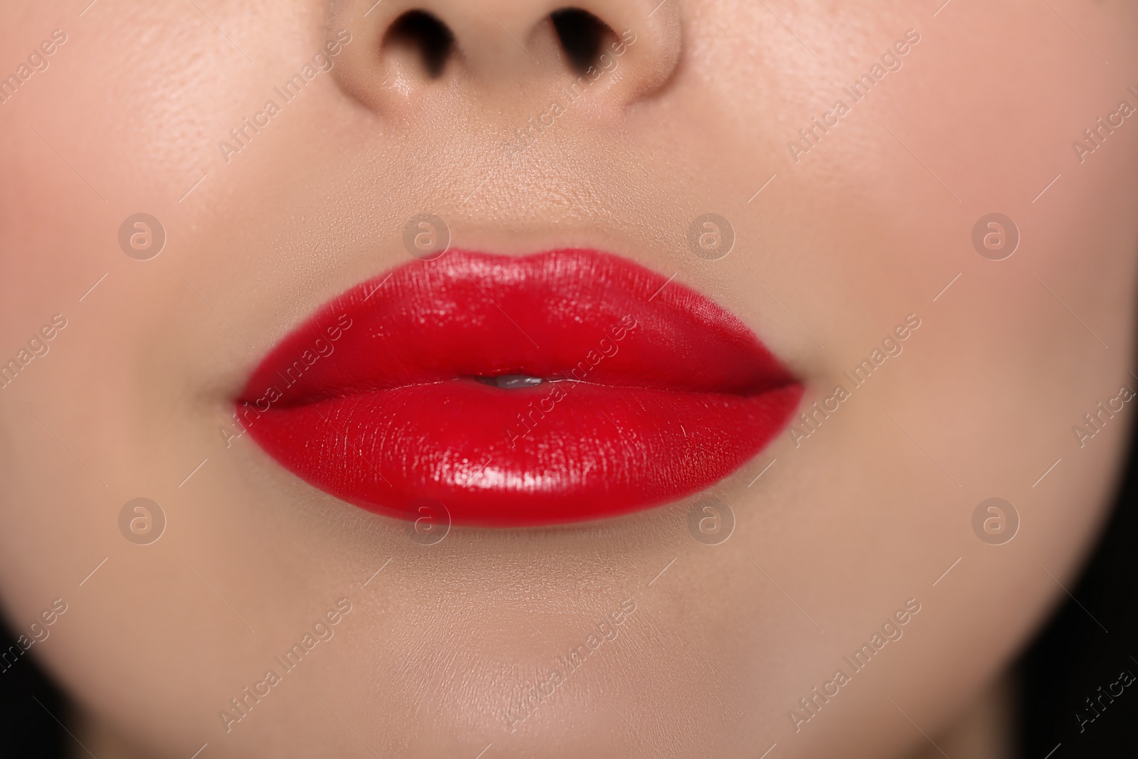 Photo of Young woman wearing beautiful red lipstick on dark background, closeup