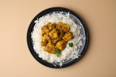 Photo of Delicious chicken curry with rice on beige background, top view