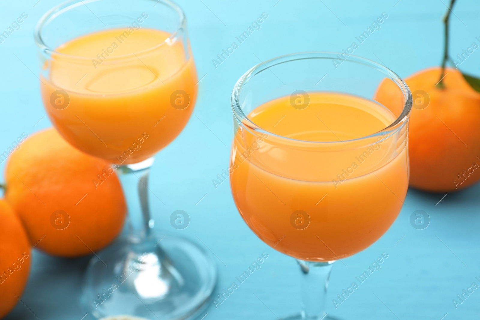 Photo of Delicious tangerine liqueur and fresh fruits on light blue table, closeup