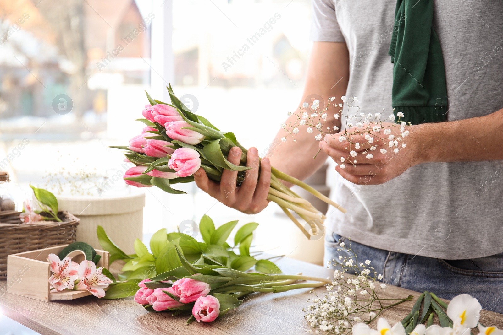 Photo of Male decorator creating beautiful bouquet at table