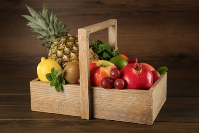 Photo of Fresh ripe fruits in crate on wooden table