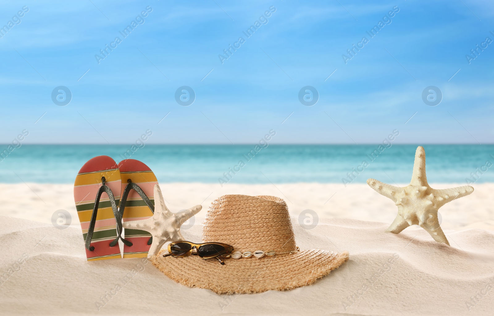 Image of Accessories and starfishes on sunny ocean beach, space for text. Summer vacation