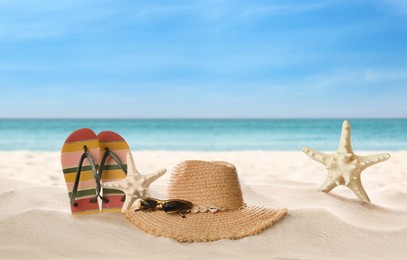 Accessories and starfishes on sunny ocean beach, space for text. Summer vacation