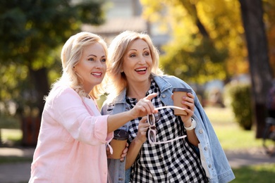 Photo of Happy mature women with coffee in park on sunny day