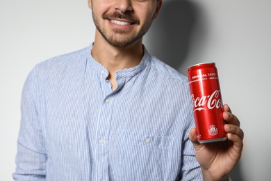 Photo of MYKOLAIV, UKRAINE - NOVEMBER 28, 2018: Young man with Coca-Cola can on white background, closeup