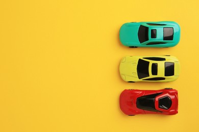 Different bright cars on yellow background, flat lay with space for text. Children`s toys