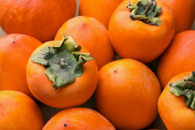 Photo of Pile of delicious ripe juicy persimmons as background, closeup