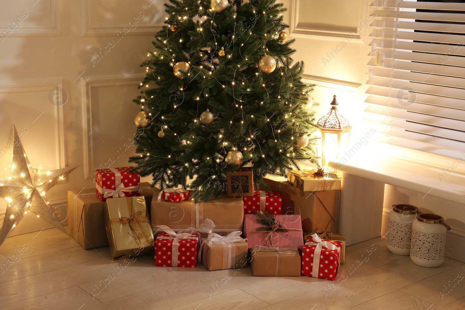 Photo of Gift boxes under Christmas tree with fairy lights indoors