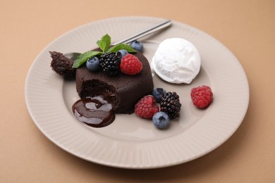 Delicious chocolate fondant served with fresh berries and ice cream on beige background, closeup