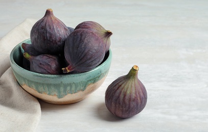 Photo of Bowl with fresh ripe figs on light background. Space for text