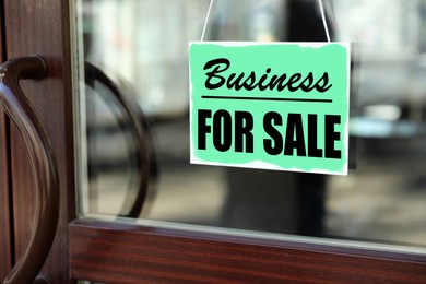 Turquoise sign with Business For Sale hanging on glass door