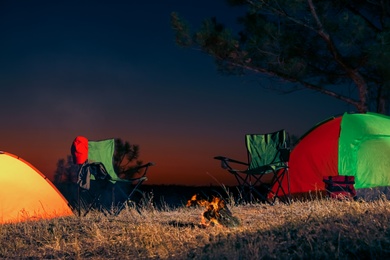 Photo of Camping tents and chairs in wilderness at night