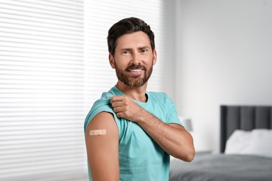 Photo of Man with sticking plaster on arm after vaccination in bedroom
