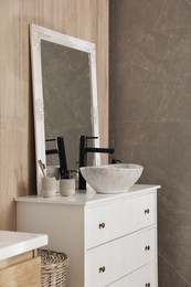 Chest of drawers with sink, mirror and toiletries in bathroom. Interior design