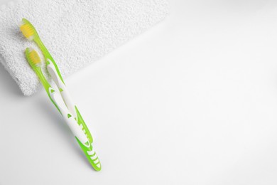 Light green toothbrushes and terry towel on white background, top view. Space for text