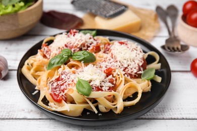 Photo of Delicious pasta with tomato sauce, basil and parmesan cheese on white wooden table
