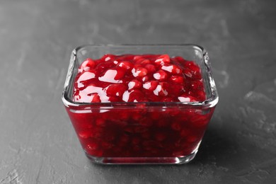 Photo of Fresh cranberry sauce in glass bowl on gray textured table, closeup