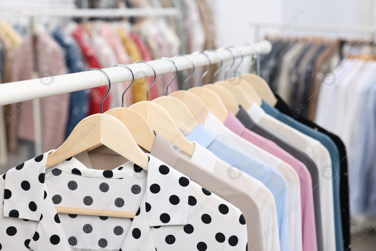 Photo of Dry-cleaning service. Many different clothes hanging on rack indoors, closeup