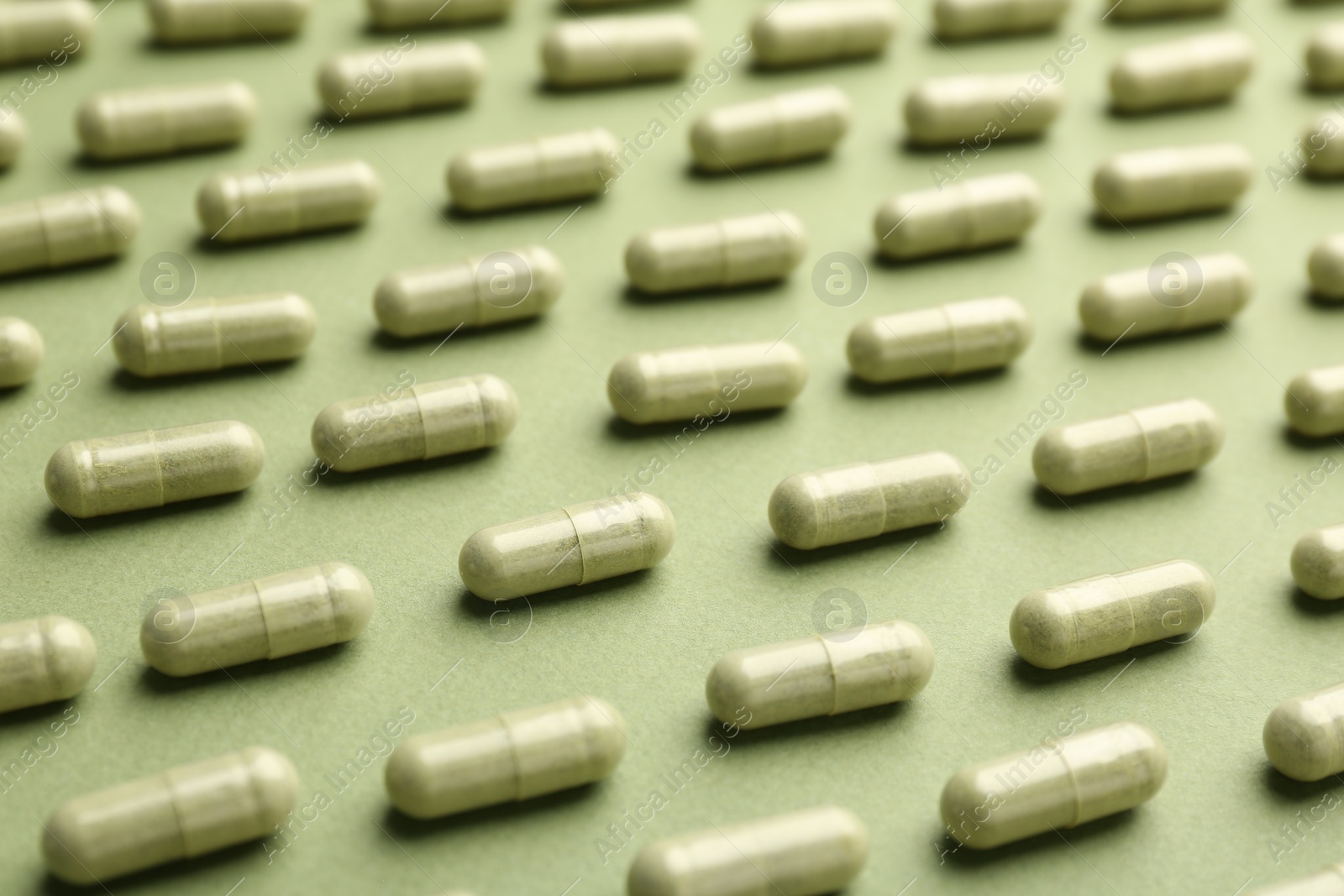 Photo of Many vitamin capsules on olive background, closeup