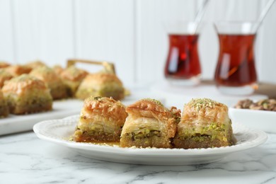 Photo of Delicious fresh baklava with chopped nuts on white marble table, closeup. Eastern sweets
