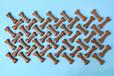 Flat lay composition with bone shaped dog cookies on light blue background