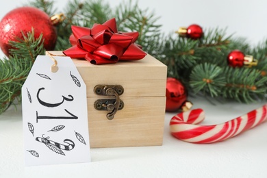 Wooden box with red bow and tag on white table. Advent calendar