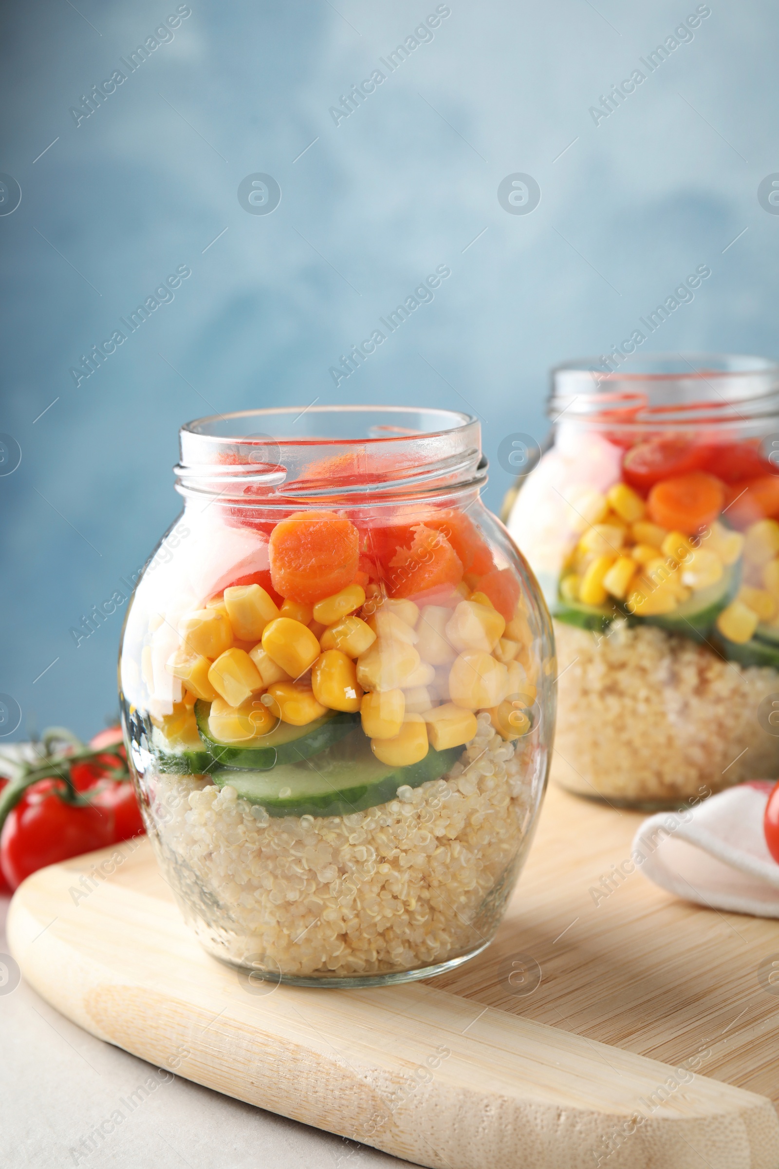 Photo of Jars with healthy quinoa salad and vegetables on table. Space for text