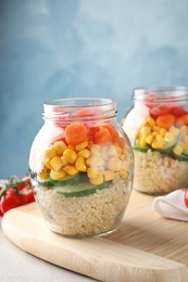 Jars with healthy quinoa salad and vegetables on table. Space for text