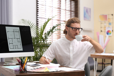 Photo of Professional interior designer drinking coffee at workplace in office