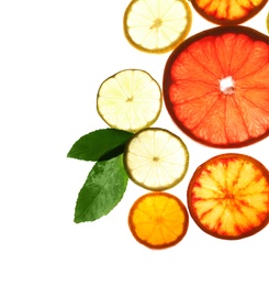 Illuminated slices of citrus fruits and leaves on white background, top view