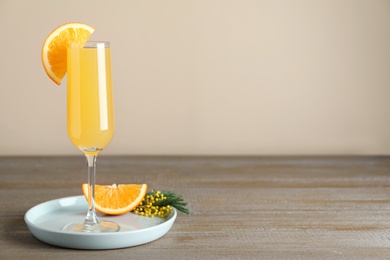 Photo of Glass of Mimosa cocktail with garnish on wooden table. Space for text