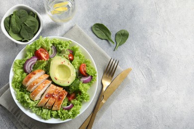 Photo of Delicious salad with chicken, avocado and vegetables served on light grey table, flat lay. Space for text
