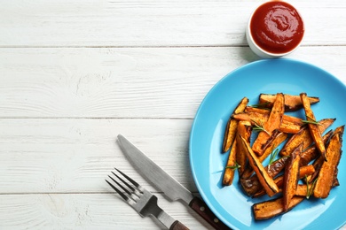 Photo of Plate with tasty sweet potato fries on wooden background, flat lay. Space for text