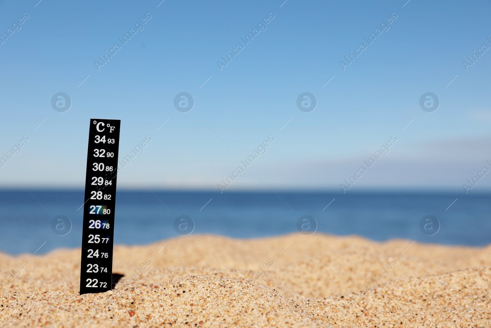 Photo of Weather thermometer in sand near sea, space for text