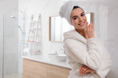 Happy young woman with towel on head in bathroom, space for text. Washing hair